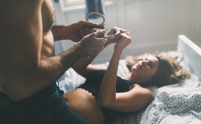 photo of a man and woman playing a domination game in bed