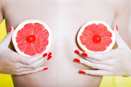 fun photo of a woman holding fruit in front of her body to represent nipples