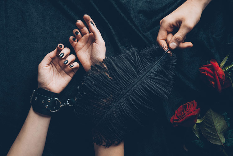 photo of a man teasing a woman by tickling her hands with a feather
