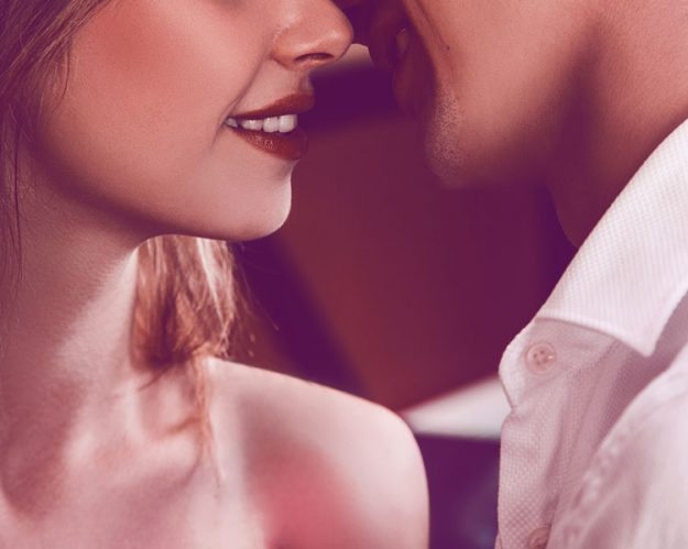man whispering a compliment in a woman's ear